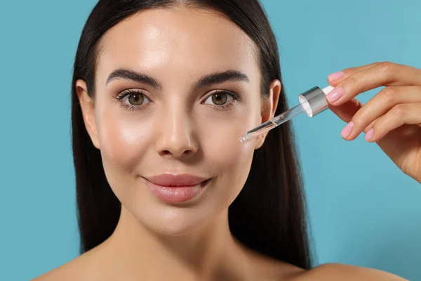 Beautiful Young Woman Applying Serum Her Face Light Blue Background — Stock Photo, Image