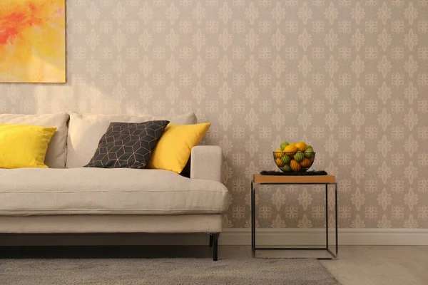 Comfortable beige sofa and side table near wall. Minimalist living room interior
