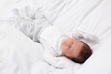 Sevimli yeni doğmuş bebek beyaz yumuşak yatakta uyuyor.