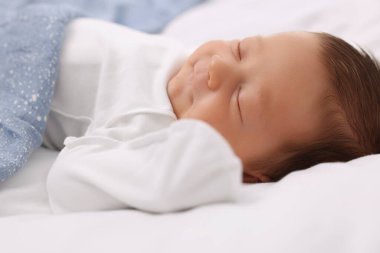 Sevimli yeni doğmuş bebek mavi battaniyenin altında uyuyor, yatakta, yakın plan