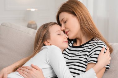 Anne evdeki kanepede tatlı kızına sarılıyor.