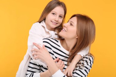 Turuncu arka planda mutlu anne ve tatlı kızının portresi.