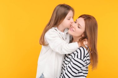 Turuncu arka planda mutlu anne ve tatlı kızının portresi. Metin için boşluk