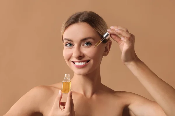 Beautiful Woman Applying Cosmetic Serum Her Face Beige Background — Stock Photo, Image