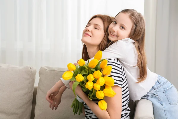 stock image Mother and her cute daughter with bouquet of yellow tulips at home. Space for text