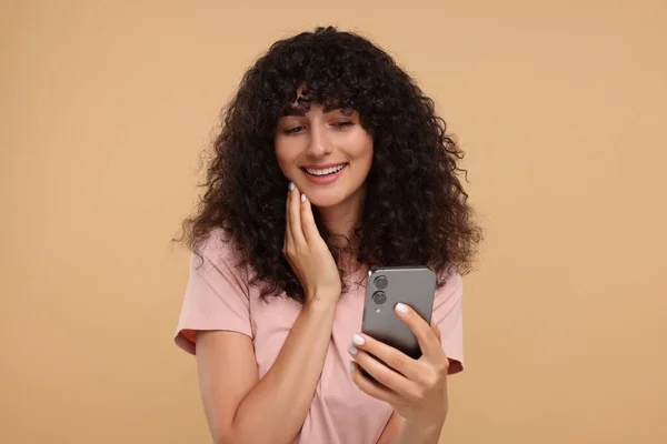 Ευτυχισμένη Νεαρή Γυναίκα Κοιτάζοντας Smartphone Μπεζ Φόντο — Φωτογραφία Αρχείου