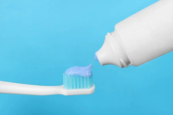 Açık Mavi Arkaplanda Diş Fırçasına Yapıştırıcı Uygulanıyor Yakın Plan — Stok fotoğraf