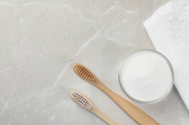 Bambu diş fırçaları, cam kâse dolusu kabartma tozu ve havlu açık gri mermer masa, düz yatak. Metin için boşluk