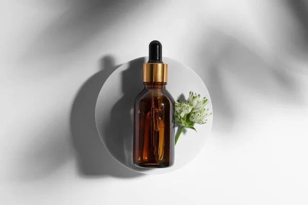 Flaska Med Kosmetisk Olja Och Blomma Vit Bakgrund Ovanifrån — Stockfoto
