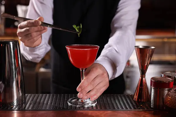 Barmen tezgahta bardakta taze Martini kokteyli hazırlıyor.