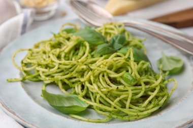 Pesto soslu lezzetli makarna ve tabakta fesleğen, yakın plan.
