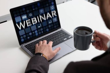 Çevrimiçi webinar, bilgisayar ekranında web sayfası. Beyaz masada dizüstü bilgisayar kullanan bir adam, yakın plan.
