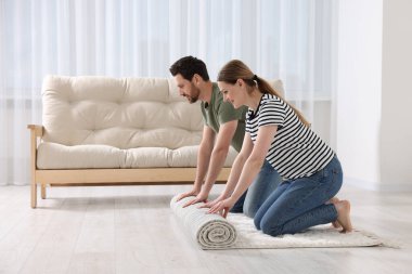 Odada güzel desenli halı seren gülümseyen bir çift. Metin için boşluk