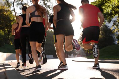 Güneşli bir günde, arka planda koşan bir grup insan.