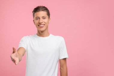 Mutlu adam karşılama ve pembe arka planda el sıkışma teklif ediyor. Metin için boşluk