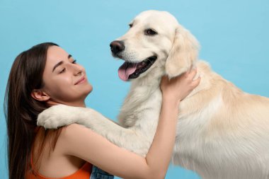 Açık mavi arka planda şirin Labrador Retriever köpeği olan mutlu bir kadın. Sevimli hayvan.