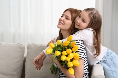 Annesi ve sevimli kızı evde bir buket sarı laleyle. Metin için boşluk