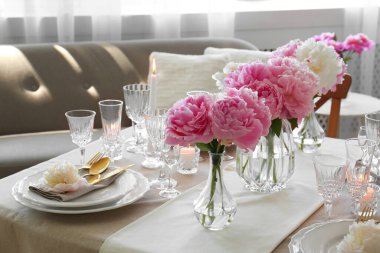 Güzel şakayıklar ve yanan mumlarla süslü bir masa.