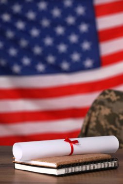 Diploma ve defterler ahşap masada Amerikan bayrağına karşı. Askeri eğitim