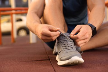 Spor salonunda antrenmandan önce ayakkabı bağcıklarını bağlayan adam, yakın plan.