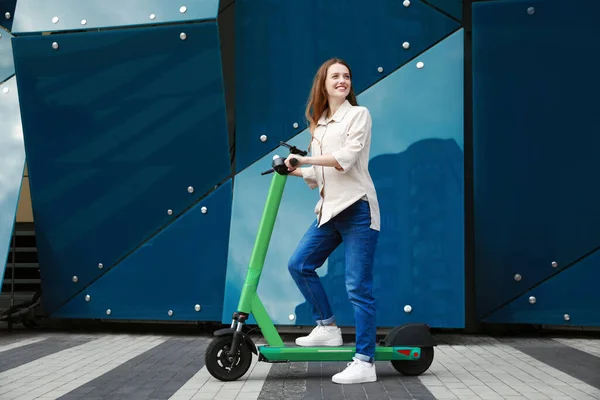 街の通りでモダンな電気キックスクーターを持つ幸せな女性 — ストック写真