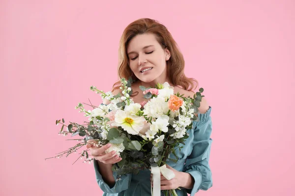 ピンクの背景に花の花束を持つ美しい女性 — ストック写真