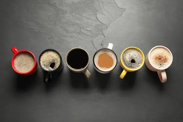 Veel Kopjes Met Verschillende Aromatische Koffie Zwarte Tafel Plat Lay — Stockfoto