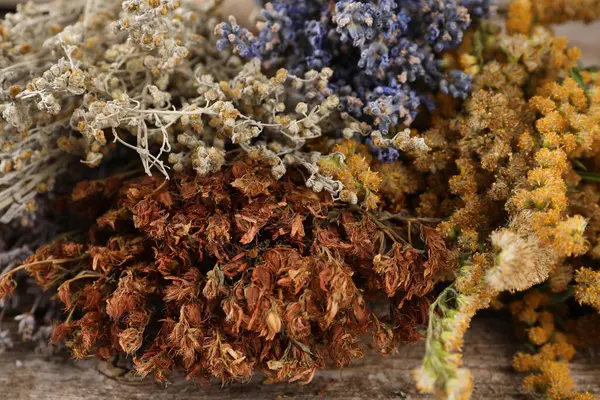 Many different dry herbs on wooden table, closeup