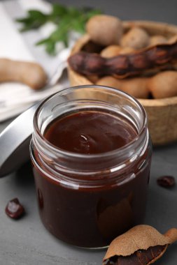 Lezzetli bir kavanoz demirhindi sosu ve gri ahşap masada taze kapsüller.