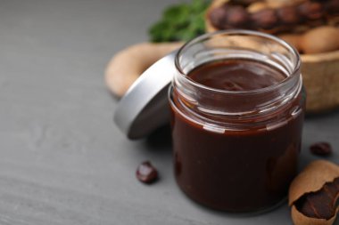 Lezzetli bir kavanoz demirhindi sosu ve gri ahşap masada taze kapsüller. Metin için boşluk