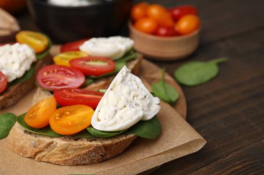 Burrata peynirli lezzetli sandviçler ve ahşap masada domatesler, yakın plan. Metin için boşluk