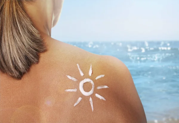 Sun protection. Woman with sunblock on her back near sea, closeup
