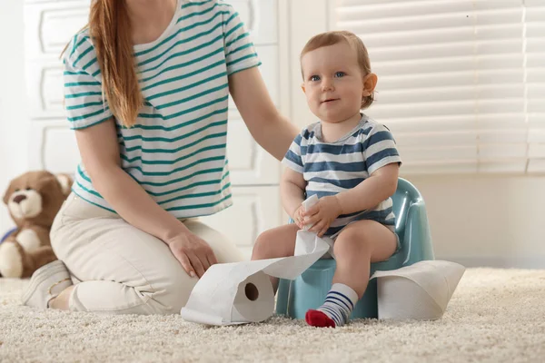 Stock image Mother training her child to sit on baby potty indoors