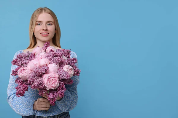 ライトブルーの背景に春の花の花束を持つ美しい女性 テキストのためのスペース — ストック写真