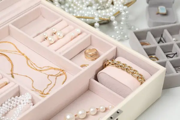 Jewelry boxes with many different accessories on white table, closeup
