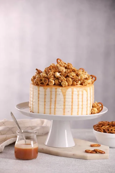 Caramel drip cake decorated with popcorn and pretzels on light table