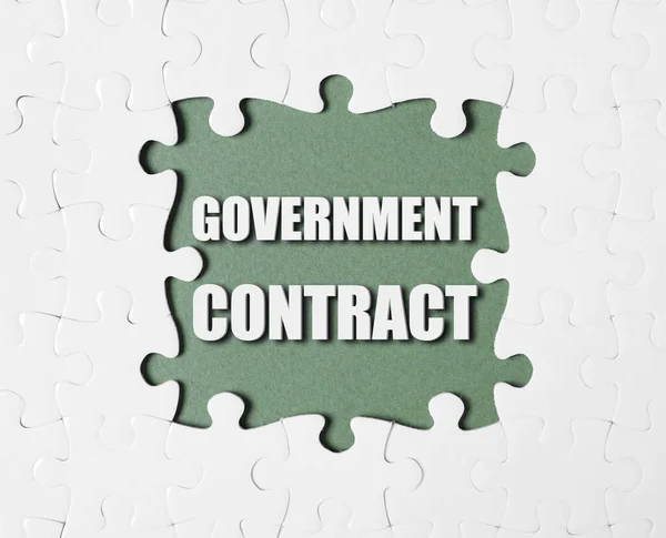 Words Government Contract surrounded by white puzzle pieces on olive color background, top view