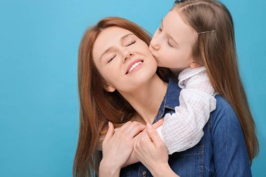 Açık mavi arka planda mutlu anne ve tatlı kızının portresi. Metin için boşluk