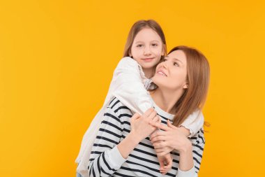 Turuncu arka planda mutlu anne ve tatlı kızının portresi. Metin için boşluk