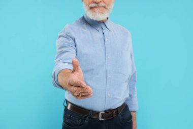 Hoş geldin diyen ve açık mavi arka planda el sıkışan adam, yakın plan.