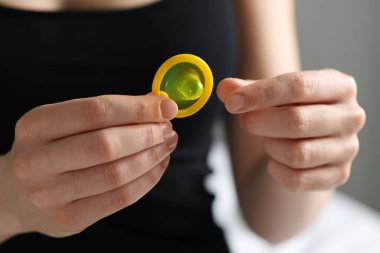 Arka planda açık prezervatif tutan kadın, yakın plan. Güvenli seks.