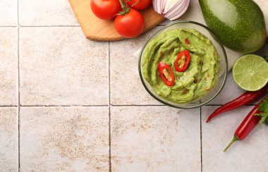 Bir kase lezzetli guacamole ve malzemeler beyaz fayanslı masada, düz yerde. Metin için boşluk