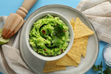 Açık mavi masada nachos cipsiyle servis edilen nefis guacamole.
