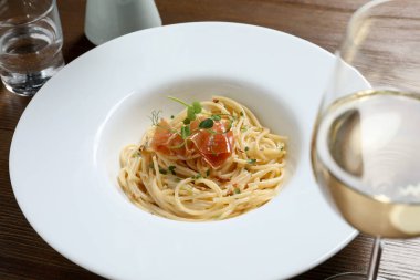 Prosciutto ve mikroyeşillikli lezzetli spagetti ahşap masada servis edilir, yakın plan. Makarna yemeğinin enfes sunumu