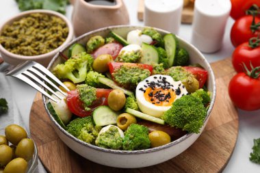 Tabakta pesto soslu lezzetli salata, malzemeler ve çatal masada, yakın plan.