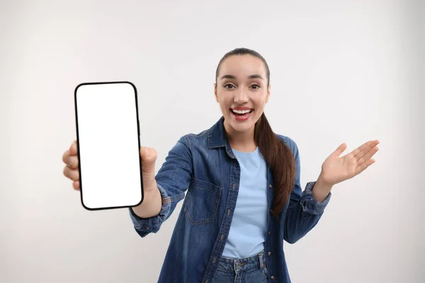 Mujer Joven Sorprendida Mostrando Teléfono Inteligente Mano Sobre Fondo Blanco —  Fotos de Stock