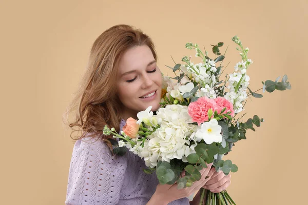 ベージュの背景に花の花束を持つ美しい女性 — ストック写真