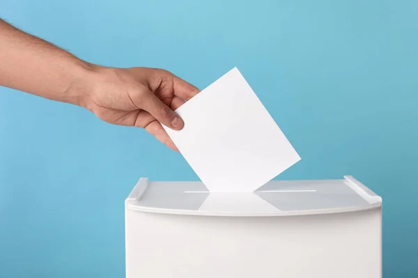 Mann Legt Seine Stimme Die Wahlurne Auf Hellblauem Hintergrund Nahaufnahme — Stockfoto