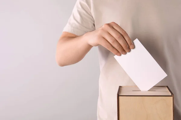 stock image Man putting his vote into ballot box on light grey background, closeup. Space for text