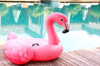 Lüks bir tatil köyünde yüzme havuzunun yanındaki tahta güvertede flamingo şeklinde süzül.